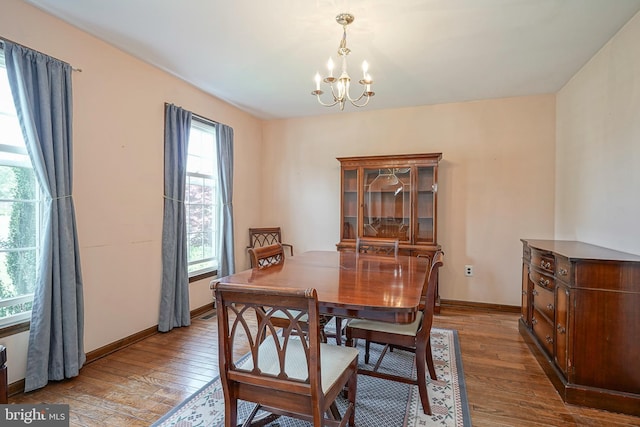 dining space with a chandelier, hardwood / wood-style flooring, and baseboards