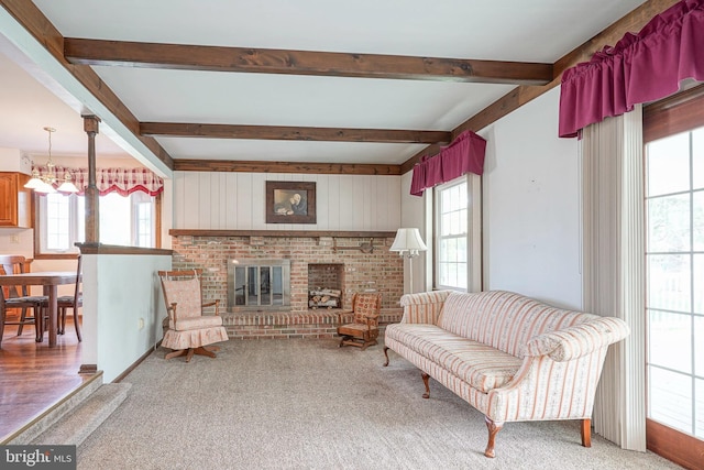 living area with a healthy amount of sunlight, beamed ceiling, and a brick fireplace