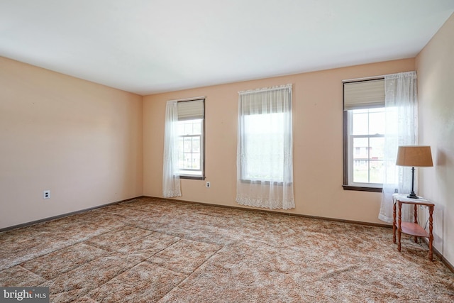 carpeted spare room featuring baseboards and plenty of natural light