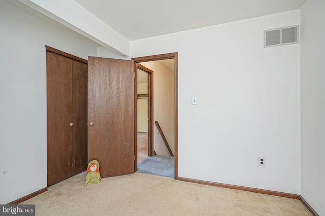 unfurnished bedroom with a closet, visible vents, carpet, and baseboards