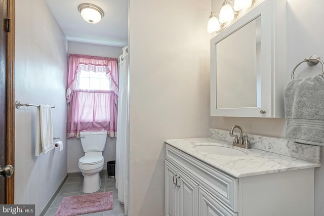 bathroom with toilet, vanity, and tile patterned flooring