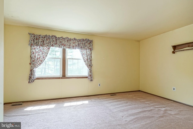 empty room featuring visible vents, carpet floors, and baseboards