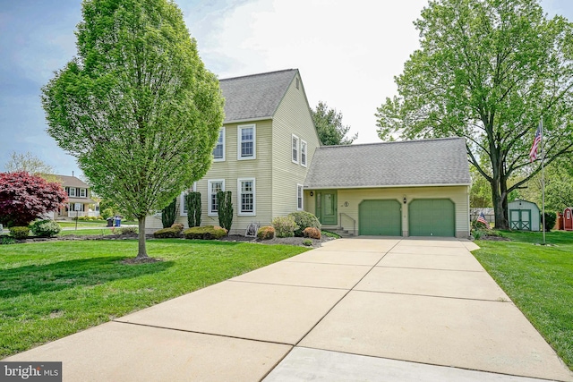 colonial home featuring concrete driveway, a shingled roof, a shed, a front yard, and a garage