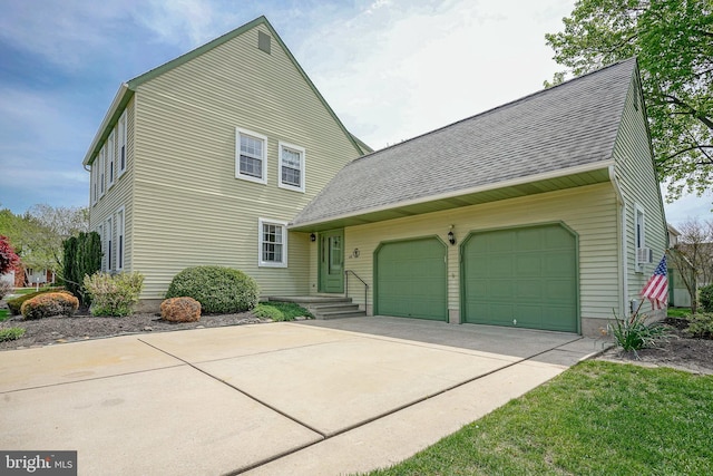 traditional-style home featuring a garage, a shingled roof, and concrete driveway