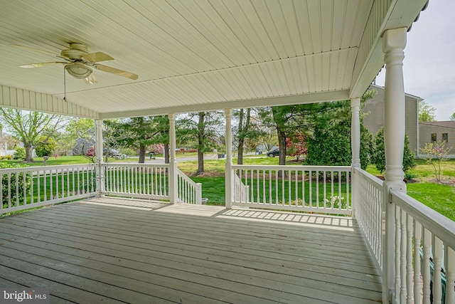 wooden terrace with ceiling fan and a yard