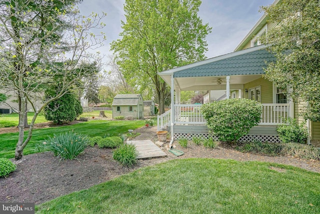view of yard featuring a shed, an outdoor structure, a ceiling fan, and covered porch