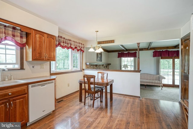 kitchen with wood finished floors, brown cabinetry, white dishwasher, backsplash, and a sink