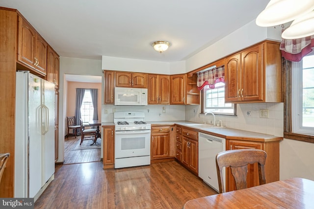 kitchen with white appliances, dark wood-style flooring, light countertops, and a sink