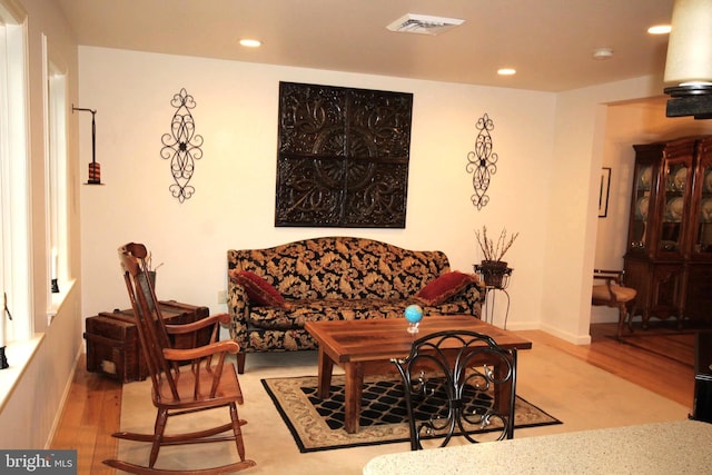 living room with recessed lighting, visible vents, wood finished floors, and baseboards