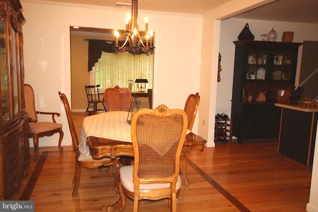 dining room featuring ornamental molding, wood finished floors, a chandelier, and baseboards