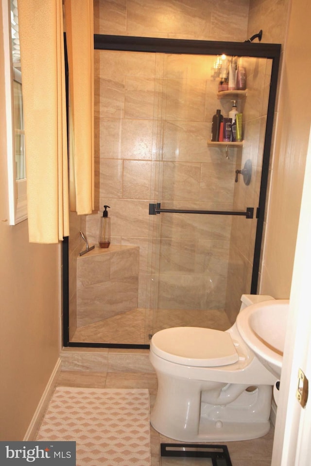 bathroom with tile patterned floors, toilet, and a stall shower