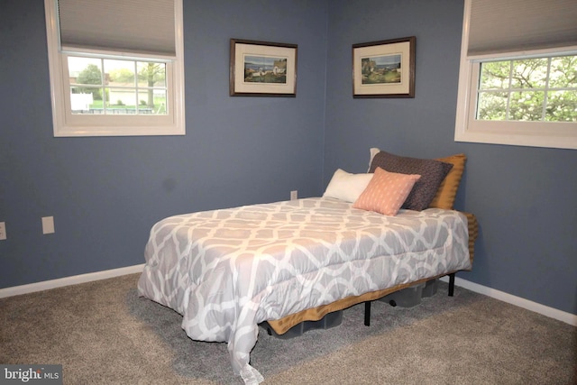 carpeted bedroom featuring multiple windows and baseboards