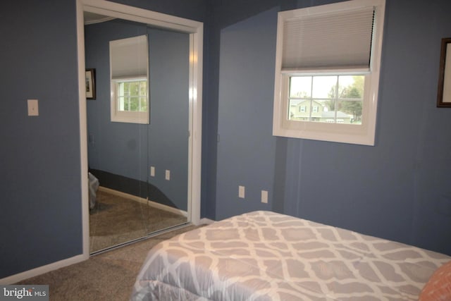 carpeted bedroom with a closet and baseboards