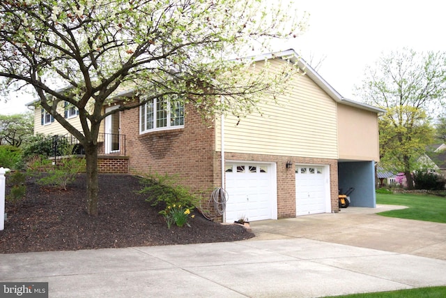 view of side of home with brick siding, concrete driveway, and an attached garage