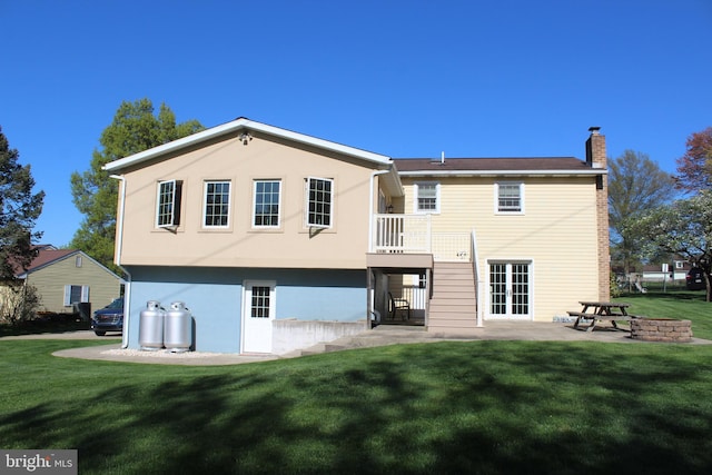 back of house featuring a chimney, a yard, and a patio area