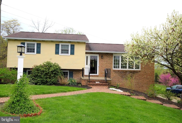 split level home featuring brick siding and a front lawn