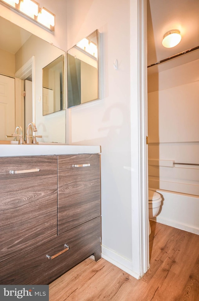 bathroom featuring toilet, wood finished floors, vanity, and baseboards
