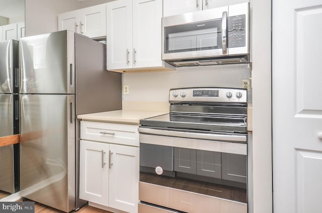 kitchen featuring stainless steel appliances, white cabinets, and light countertops