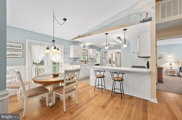 dining space with visible vents, vaulted ceiling, and light wood-type flooring