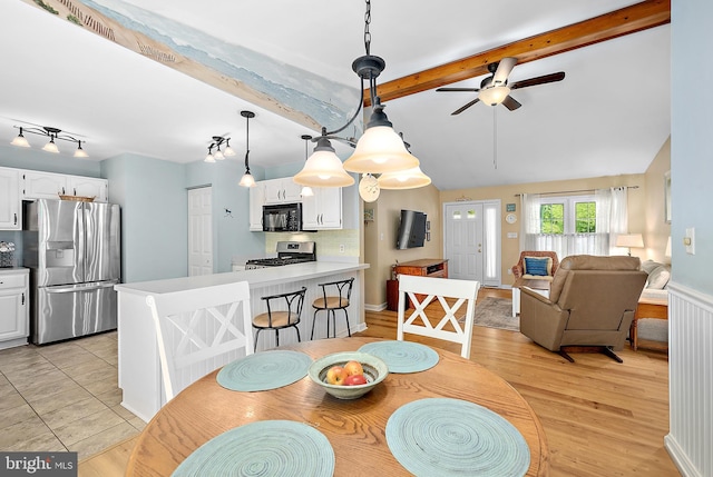 dining area featuring a ceiling fan and lofted ceiling with beams