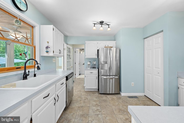 kitchen featuring appliances with stainless steel finishes, a sink, baseboards, light countertops, and white cabinetry