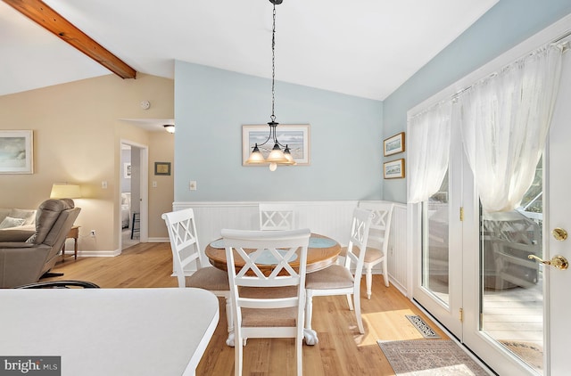 dining room featuring visible vents, an inviting chandelier, light wood-type flooring, a wainscoted wall, and lofted ceiling with beams