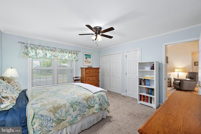 bedroom featuring crown molding, carpet, ceiling fan, and two closets