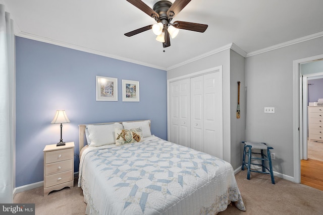 carpeted bedroom with baseboards, ornamental molding, a ceiling fan, and a closet
