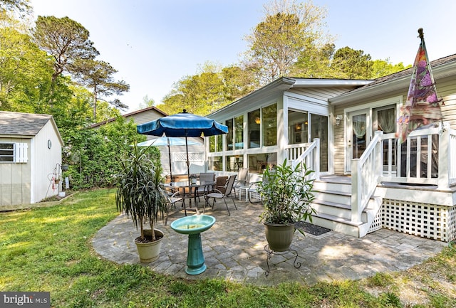 back of house featuring a storage unit, a sunroom, an outbuilding, a patio, and a yard
