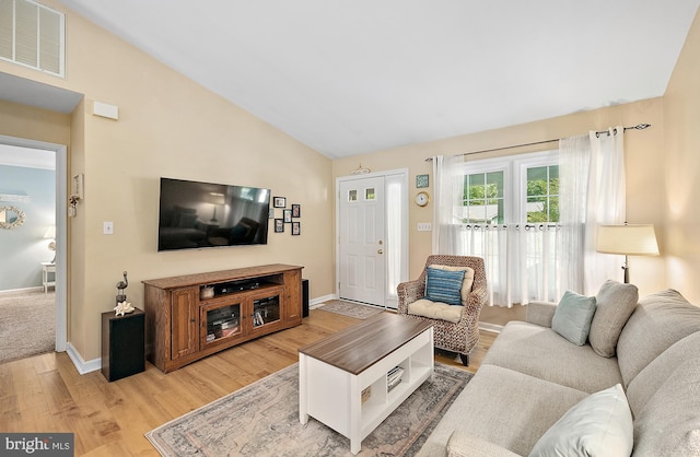 living area featuring visible vents, baseboards, light wood-style flooring, and lofted ceiling
