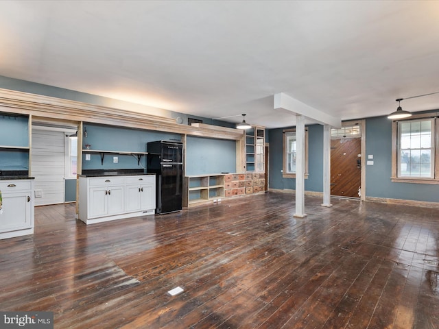 unfurnished living room with dark wood-style flooring and baseboards