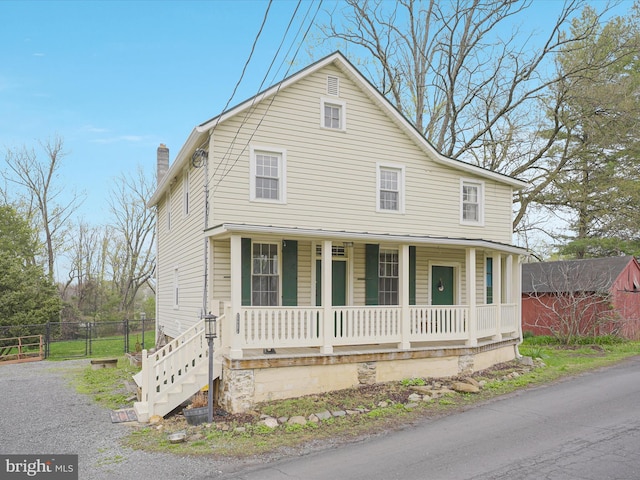 view of front of home with a porch, fence, and a chimney