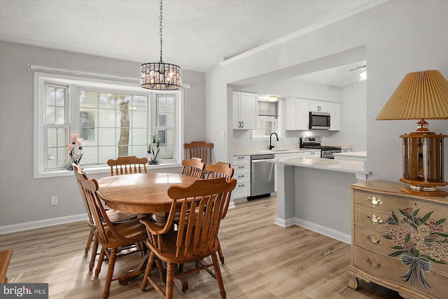 dining area featuring a textured ceiling, a chandelier, light wood finished floors, baseboards, and ornamental molding