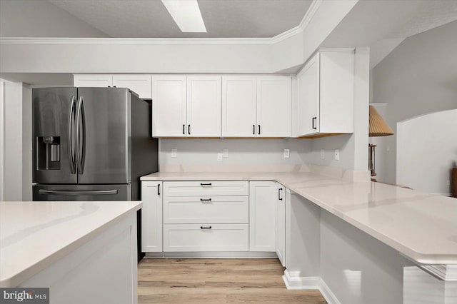 kitchen featuring stainless steel fridge, white cabinetry, light wood-style flooring, ornamental molding, and light stone countertops