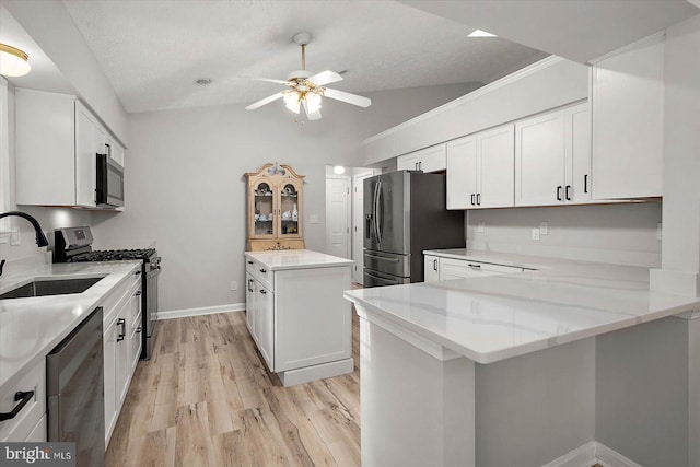 kitchen featuring appliances with stainless steel finishes, a sink, lofted ceiling, a kitchen island, and ceiling fan