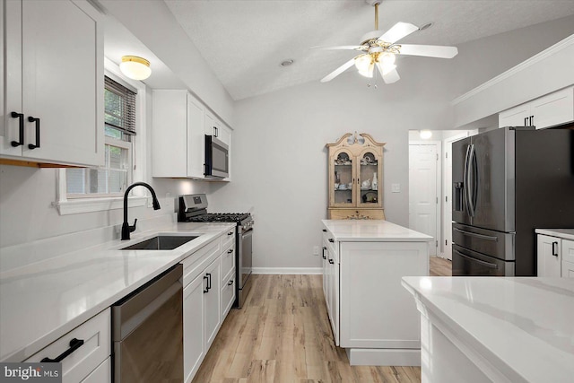 kitchen featuring stainless steel appliances, a sink, a center island, vaulted ceiling, and ceiling fan