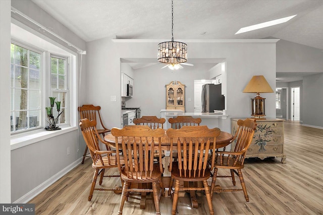 dining space with lofted ceiling, light wood finished floors, a chandelier, baseboards, and a skylight