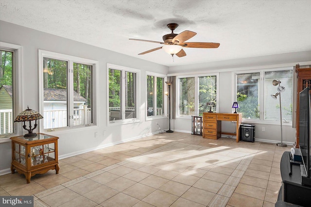 sunroom with tile patterned flooring, plenty of natural light, baseboards, and a textured ceiling