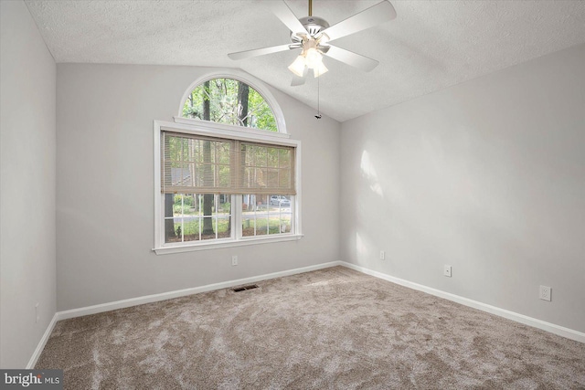 carpeted spare room featuring a textured ceiling, vaulted ceiling, a ceiling fan, and baseboards