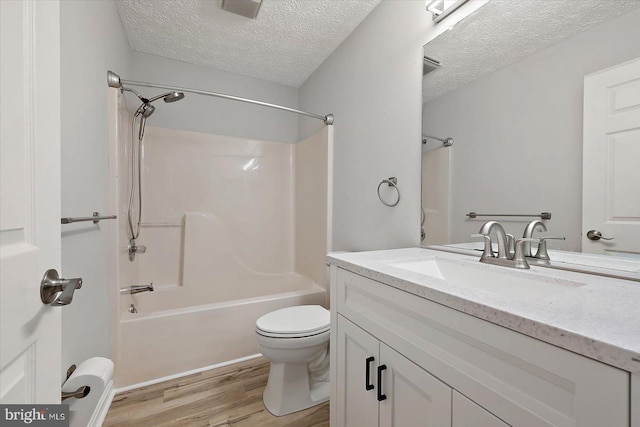 full bathroom featuring wood finished floors, a textured ceiling, vanity, toilet, and washtub / shower combination