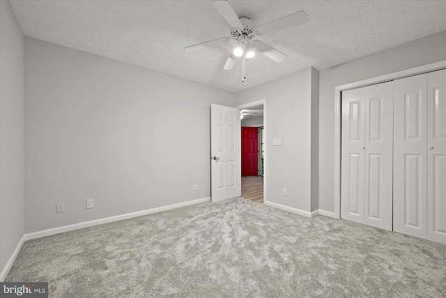 unfurnished bedroom featuring carpet, a textured ceiling, baseboards, and a closet