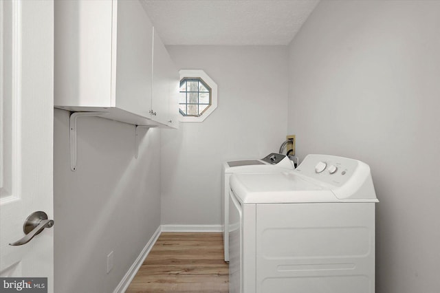 washroom with separate washer and dryer, cabinet space, light wood-style flooring, a textured ceiling, and baseboards