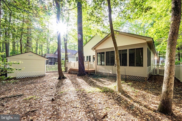 view of side of property with a sunroom, a wooden deck, crawl space, an outdoor structure, and fence