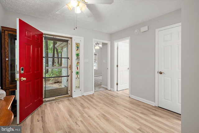 foyer entrance featuring a ceiling fan, a textured ceiling, wood finished floors, and baseboards