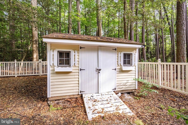 view of shed with fence and a forest view