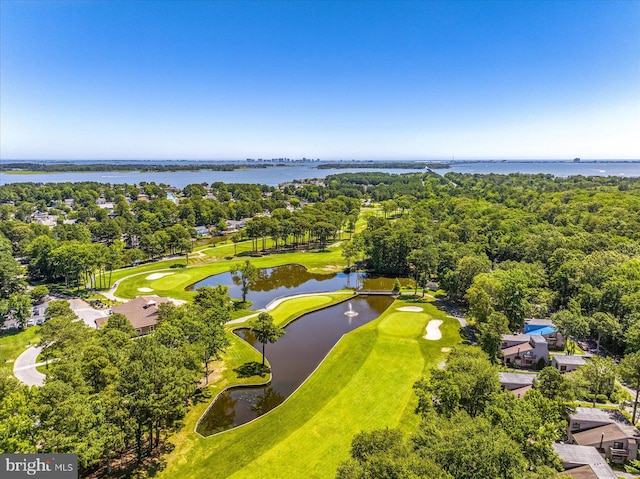 drone / aerial view of a nearby body of water, a golf course, and a tree filled landscape