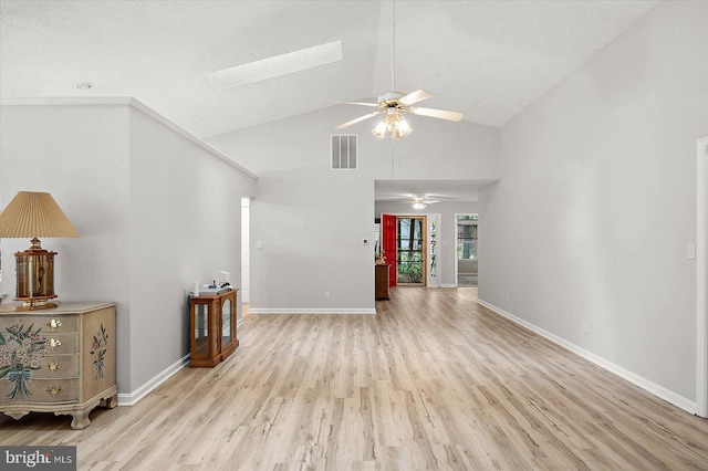 unfurnished room featuring a ceiling fan, light wood finished floors, a skylight, baseboards, and high vaulted ceiling