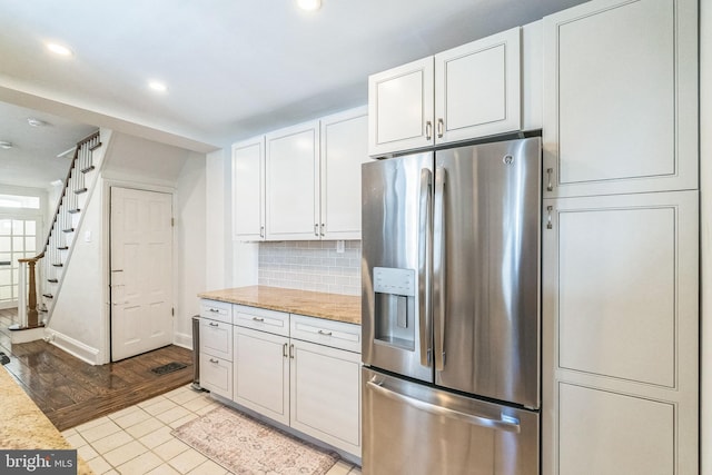 kitchen with tasteful backsplash, recessed lighting, white cabinets, and stainless steel refrigerator with ice dispenser
