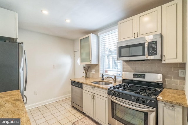 kitchen with tasteful backsplash, baseboards, light tile patterned floors, stainless steel appliances, and a sink