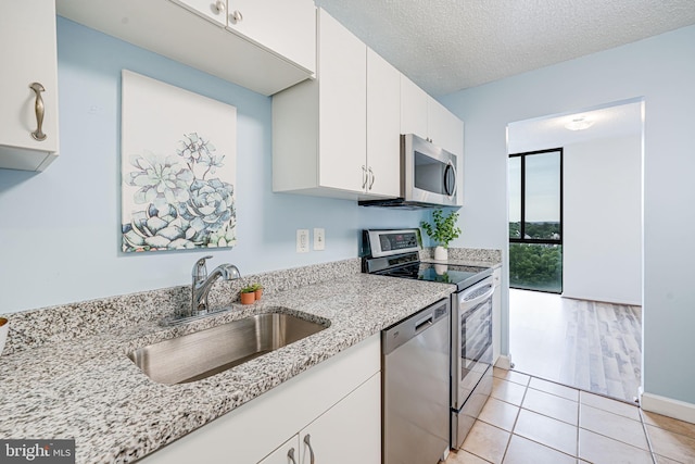 2311 Pimmit Dr Unit 1102, Falls Church, VA 22043 - kitchen featuring appliances with stainless steel finishes, a sink, white cabinets, light stone countertops, and a textured ceiling